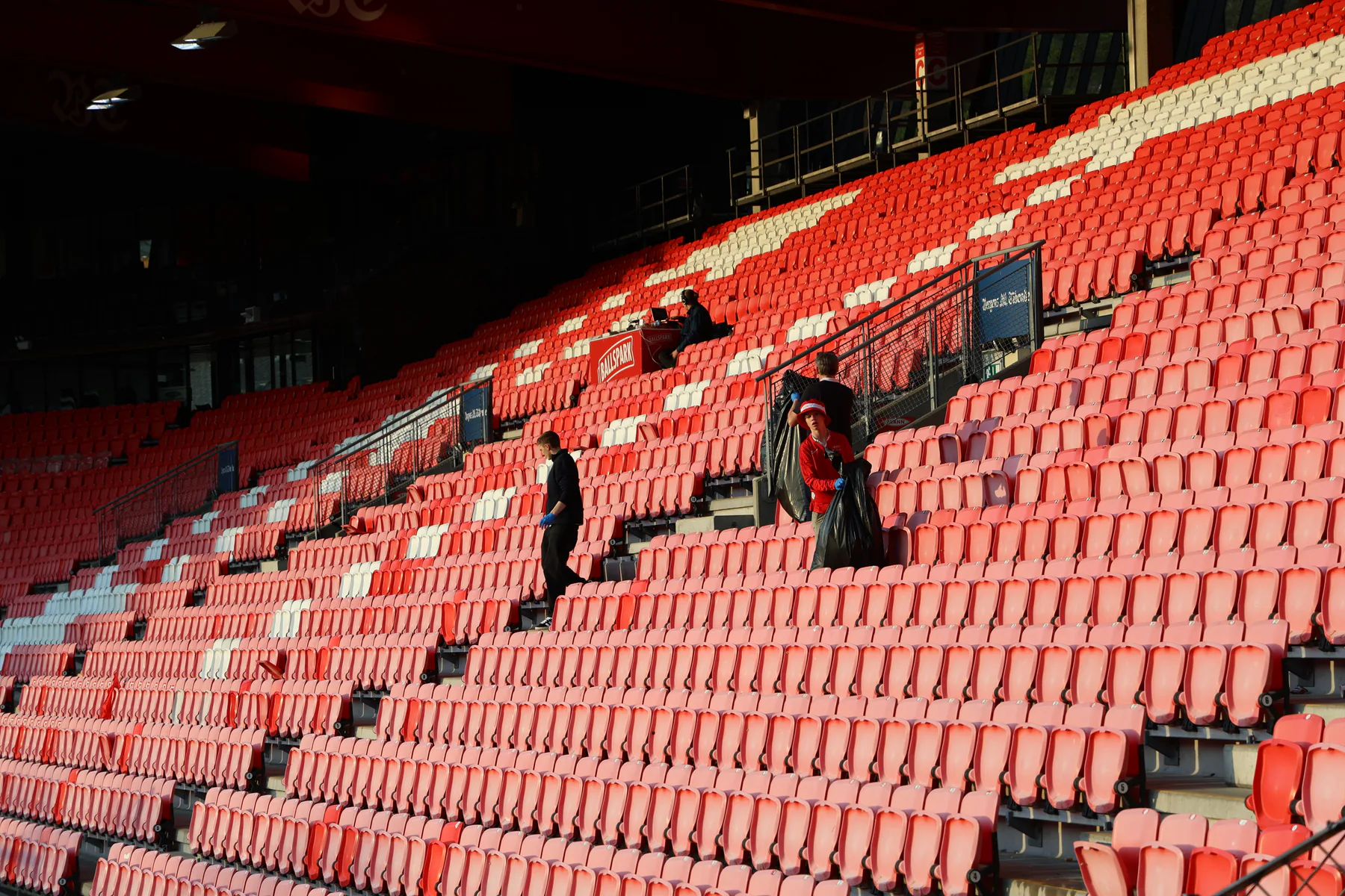 Volunteers collecting waste among red stadium seats