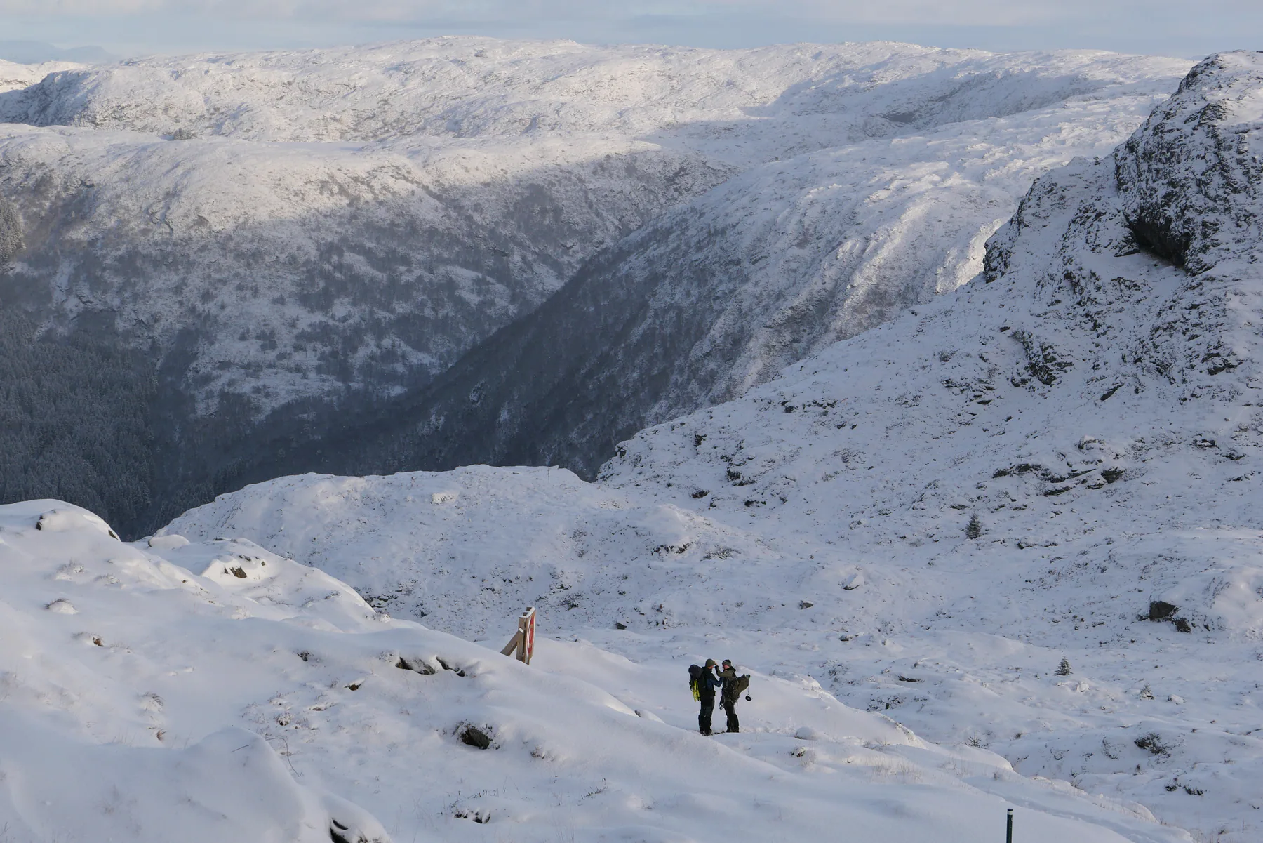 Two hikers standing in an expansive snow-covered mountain landscape